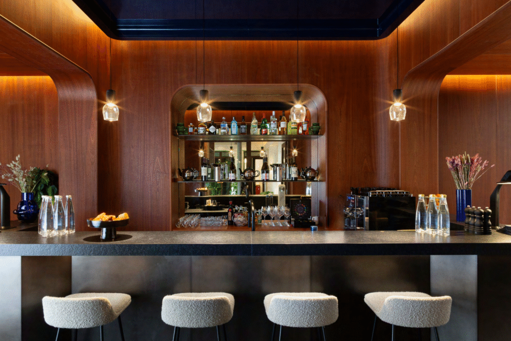 Bar central avec tabourets et éclairage tamisé, réaménagement d’un immeuble de bureaux de luxe à Paris.